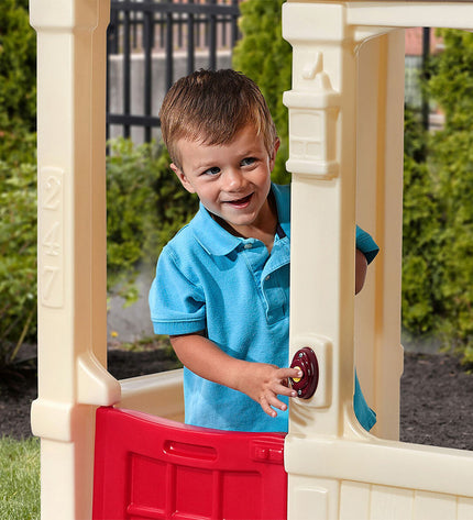 Step 2 Courtyard Cottage playhouse for children, featuring windows, door, and colorful exterior in a backyard setting.
