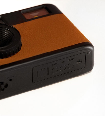 Camp Snap CS-V105-BR-WW digital camera in black, showing front view with lens, buttons, and brand logo for photography and videography.