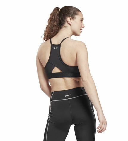 Reebok black sports bra with strappy design, suitable for outdoor cycling and sports activities, shown on a model.