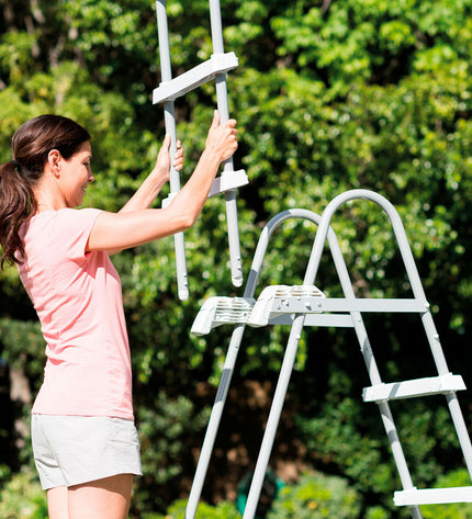 Intex zwembad ladder in outdoor garden setting, sturdy plastic steps and handrails for easy access to above-ground pools.