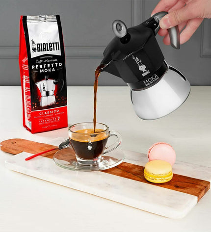 Black Bialetti Italian coffee pot in aluminium for home brewing, shown on a kitchen countertop.