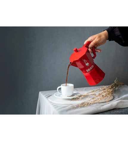 Red Bialetti Moka Express Italian coffee pot in aluminum with three cups, ideal for brewing authentic espresso at home.