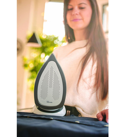 POLTI Q100 steam iron with 2400 W power, shown on a ironing board ready for use, in a home laundry setting.