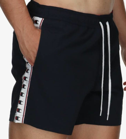 Black Champion men's swim trunk for sports and outdoor watersports, shown on a model at the beach.
