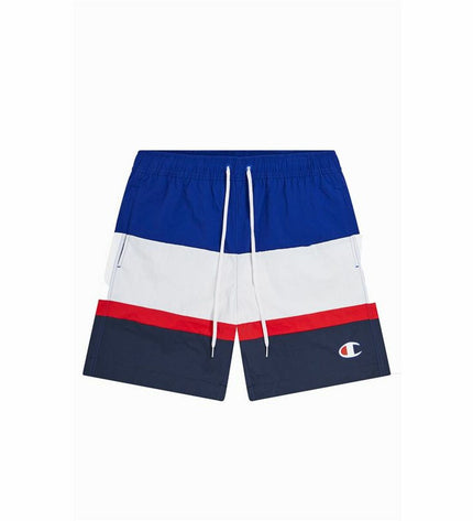Champion men's blue swim trunks for sports and outdoor watersports, shown on a model at the beach.