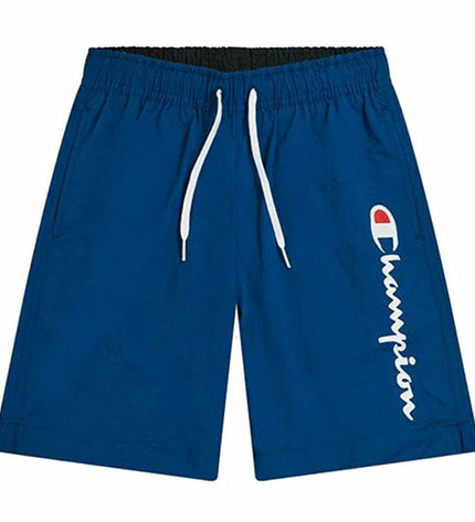 Child wearing a blue Champion swim set for kids, suitable for water sports and outdoor activities, on a sandy beach.