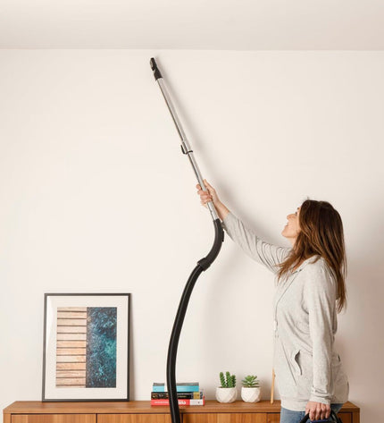 Taurus Guzzler Cyclone steel vacuum cleaner with 850W power, shown in a home cleaning setting with attachments.