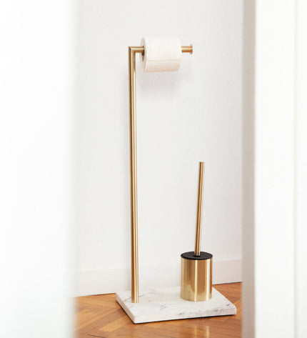 Gold toilet paper holder with integrated toilet brush stand from Andrea House, mounted on a bathroom wall.