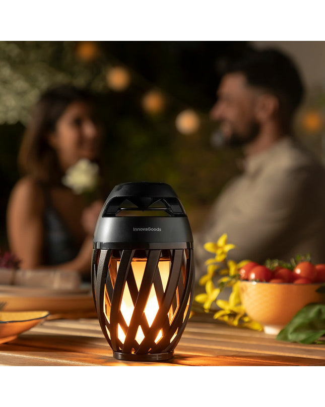 InnovaGoods draadloze speakerphone with LED-vlameffect, outdoor garden decor, portable speaker with colorful flame lighting in a garden setting.