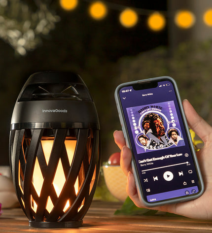 Wireless speakerphone with LED flame effect in outdoor garden decor, by InnovaGoods, featuring a modern design and vibrant lighting.