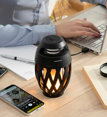 Wireless speakerphone with LED flame effect by InnovaGoods, outdoor garden decoration with colorful flickering light display.