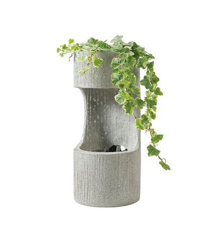 Lifetime Tuinfontein waterbron in cilindrische design, outdoor garden decor with a rustic stone finish showing water feature details.