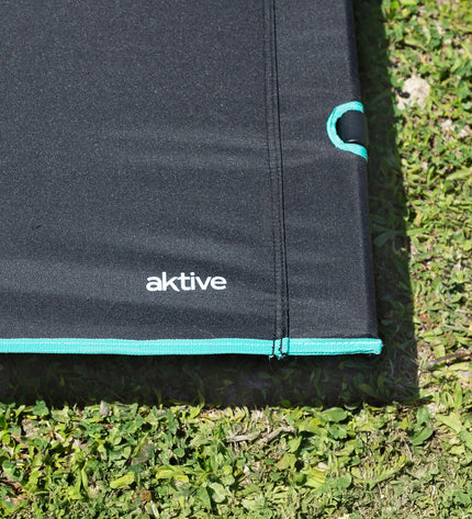 Two Aktive camping beds in green and black with metal frames, measuring 193 x 14.5 x 67 cm, for outdoor camping and hiking.