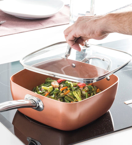 InnovaGoods Copper 5-in-1 ceramic cookware set with four kitchen utensils, including pans and lids, on a kitchen countertop.